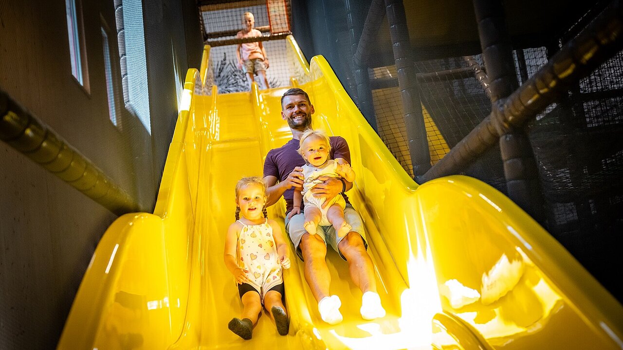 Papa rutscht mit Kindern im Elldus Resort die Rutsche herunter 