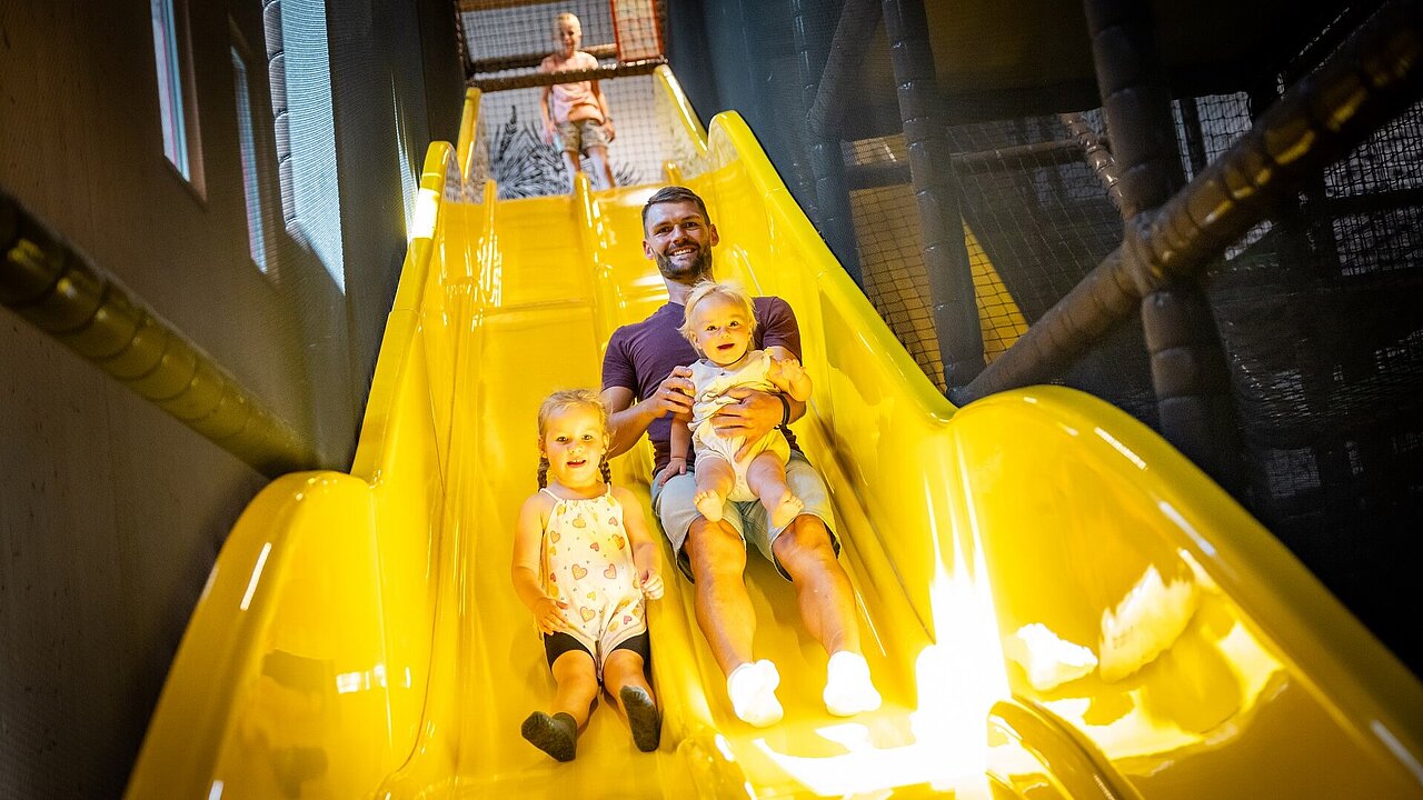 Papa rutscht mit Kindern im Elldus Resort die Rutsche herunter