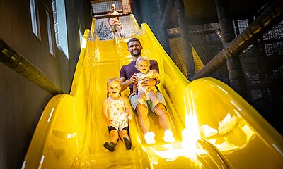 Papa rutscht mit Kindern im Elldus Resort die Rutsche herunter 