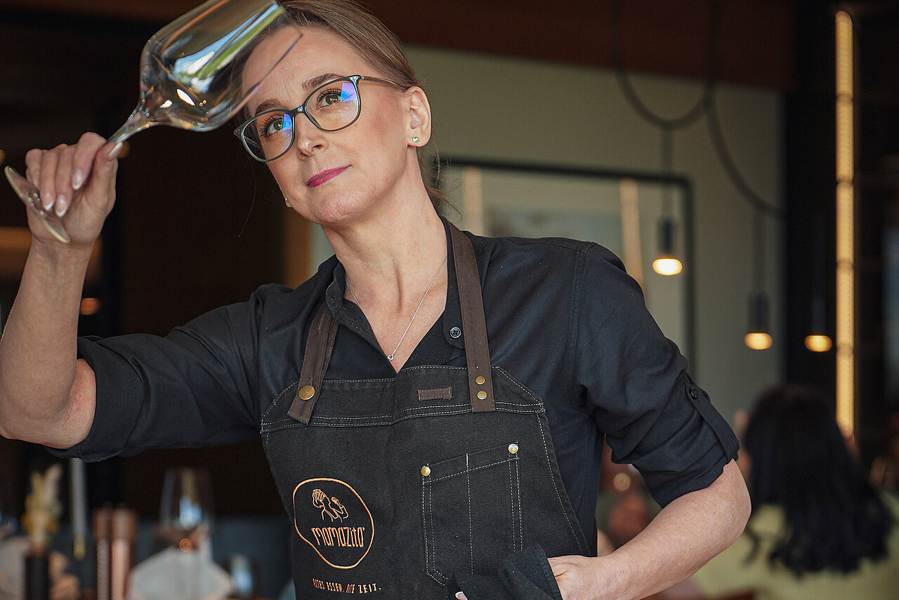 Restaurantkauffrau (m/w/d) im Elldus Rsort Eine gewissenhafte Servicemitarbeiterin beim Polieren eines Weinglases.